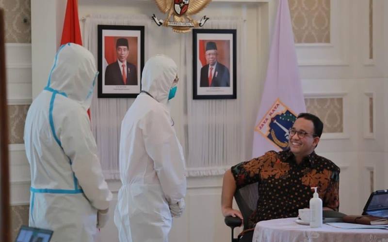 Gubernur DKI Jakarta Anies Baswedan dua dua tenaga kesehatan mengenakan alat pelindung diri (APD). Anies psoitif Covid-19 dan dalam masa isolasi mandiri. JIBI - Bisnis/Nancy Junita @kawalCOVID19