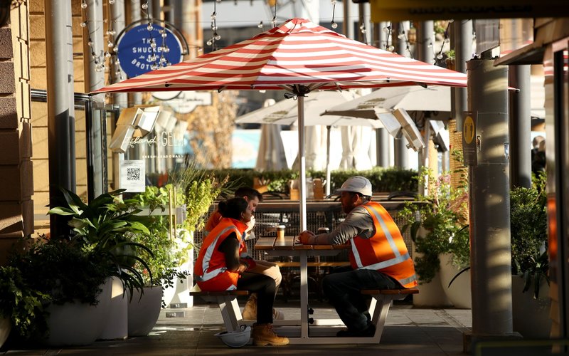 Petugas kontruksi tengah menikmati kopi di sebuah kafe, di Selandia Baru -  Bloomberg