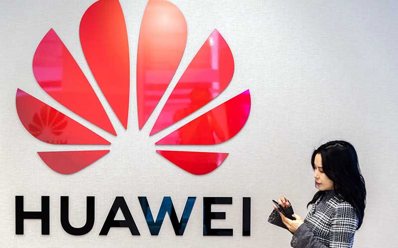 Warga menggunakan smartphone di dekat logo Huawei Technologies Co. di Brussels, Belgia, Selasa (21/5/2019). Bloomberg - Geert Vanden Wijngaert
