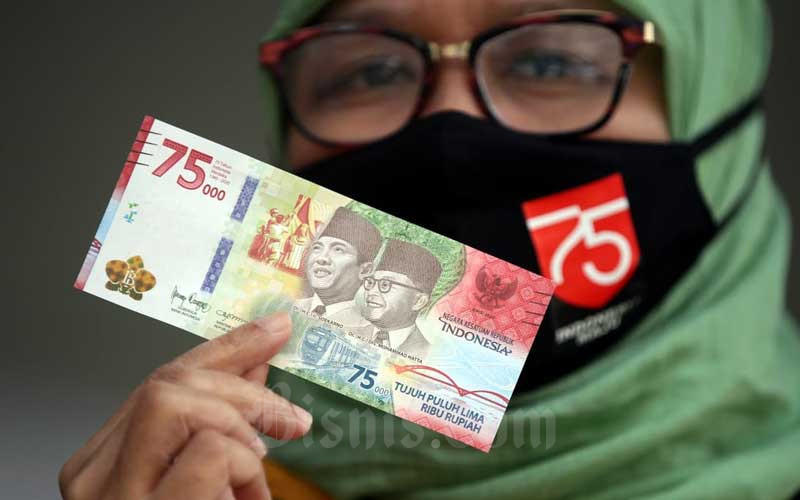 Warga memperlihatkan uang lembar pecahan Rp75.000 usai melakukan penukaran di Kantor Perwakilan wilayah Bank Indonesia (KPw BI) Jawa Barat, Bandung, Jawa Barat, Selasa (18/8/2020). Bisnis - Rachman