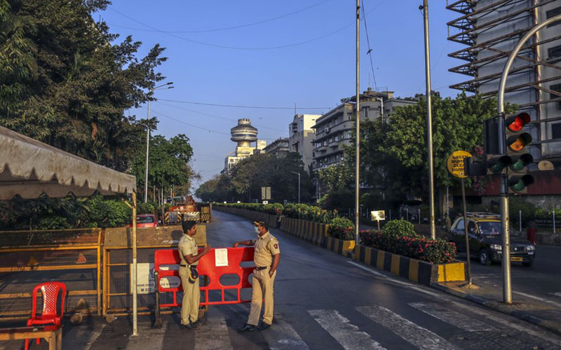 Dua petugas polisi berjaga-jaga di Kota Mumbai, India, seiring dengan pemberlakuan lockdown untuk mencegah penyevaran virus corona COVID-19. - Bloomberg