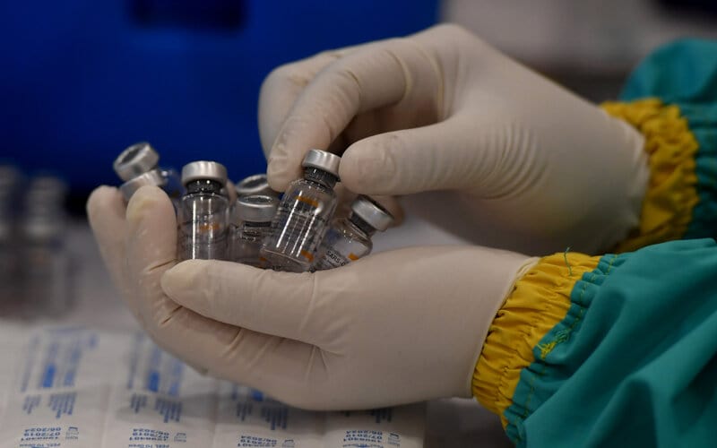 Petugas kesehatan mengumpulkan botol vaksin Covid-19 produksi Sinovac yang telah digunakan saat pelaksanaan vaksinasi massal di Surabaya, Jawa Timur, Minggu (31/1/2021). Vaksinasi massal tersebut diikuti kurang lebih 5.000 tenaga kesehatan. - Antara/Zabur Karuru