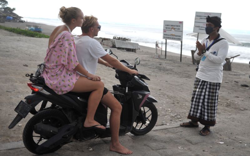 Pecalang atau petugas pengamanan adat Bali memberikan penjelasan kepada wisatawan mancanegara. - Antara/Fikri Yusuf