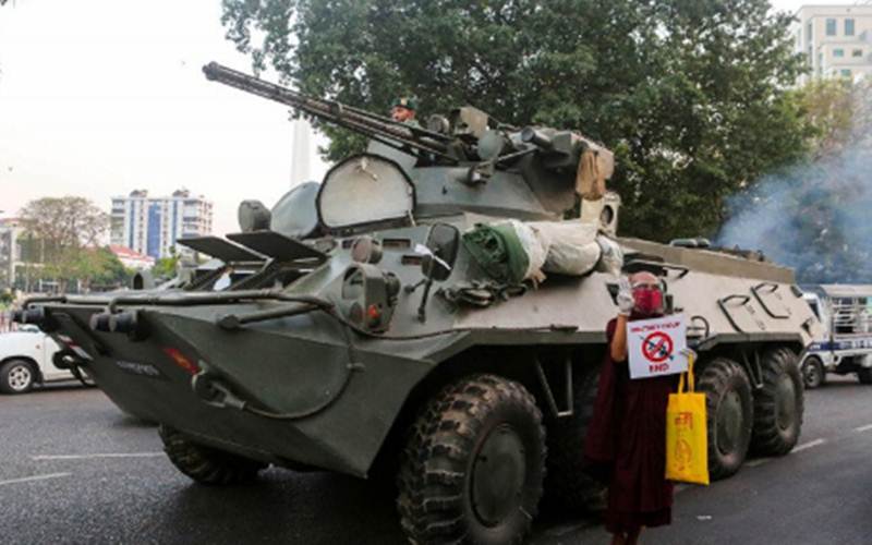 Seorang biksu Buddha memegang tanda berdiri di samping kendaraan lapis baja saat protes terhadap kudeta militer, di Yangon, Myanmar, Minggu (14/2/2021)./Antara - Reuters/Stringer