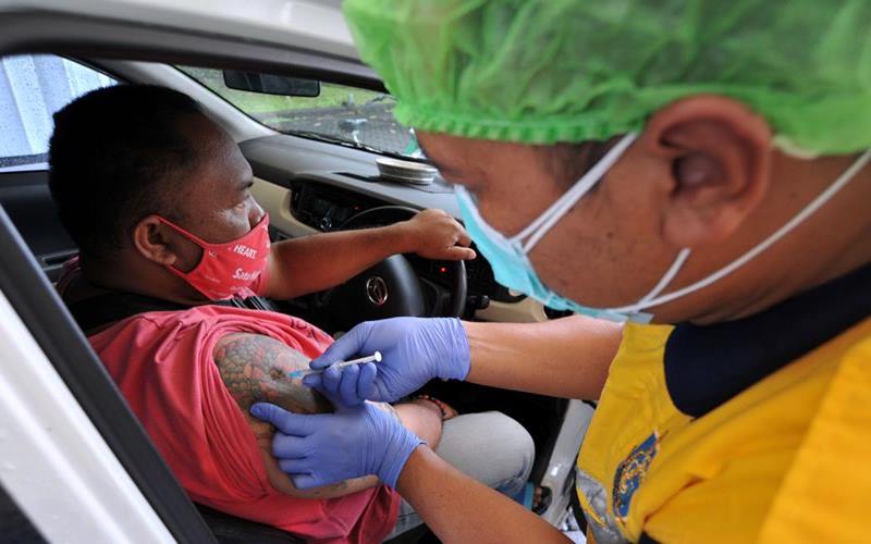 Vaksinator menyuntikkan vaksin Covid-19 kepada pekerja sektor pariwisata yang berada di atas kendaraan saat vaksinasi Covid-19 dengan sistem 'drive thru', di Nusa Dua, Badung, Bali, Minggu (28/2/2021). Layanan vaksinasi dengan sistem 'drive thru' yang dilaksanakan Kementerian Kesehatan berkolaborasi dengan Grab dan Good Doctor tersebut merupakan layanan pertama yang dihadirkan di kawasan Asia Tenggara guna membantu mempercepat pelaksanaan vaksinasi Covid-19 di Indonesia. - Antara