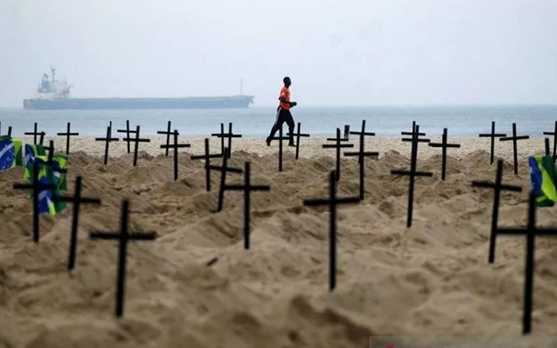 Seorang pria berlari melewati ratusan makam yang digali oleh aktivis LSM Rio de Paz di Pantai Copacabana, menyimbolkan warga yang meninggal dunia akibat penyakit  Covid-19 di Rio de Janeiro, Brasil, Kamis (11/6/2020). - Antara/Reuters