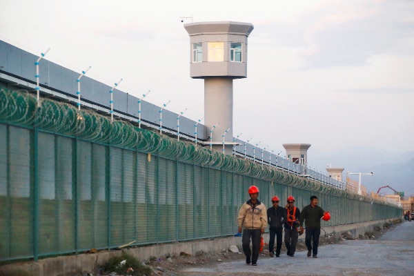 Ilustrasi - Beberapa pekerja berjalan di luar pagar lokasi yang secara resmi disebut sebagai pusat edukasi vokasional di Dabancheng, Xinjiang, Wilayah Otonomi Uighur, China, Selasa (4/9/2018). - Reuters/Thomas Peter