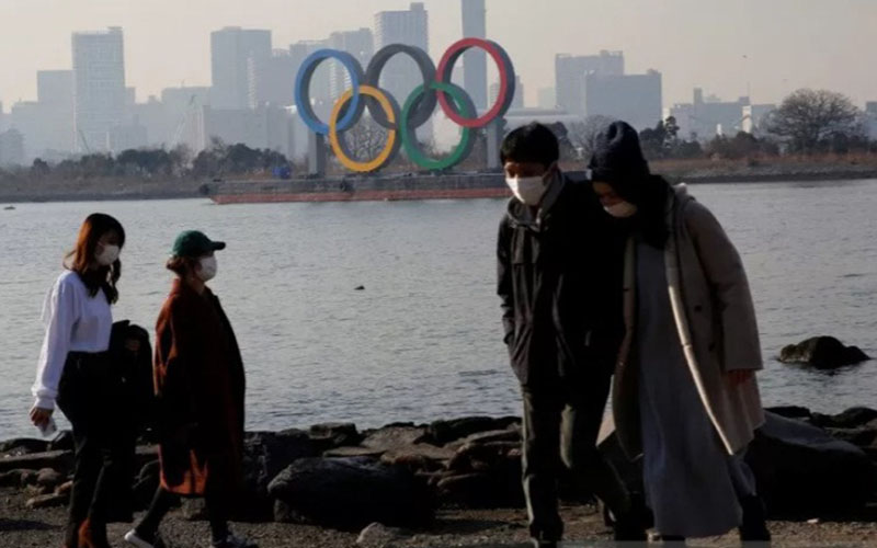 Warga memakai masker untuk mencegah penularan virus Covid-19 dengan latar belakang cincin Olimpiade raksasa di Tokyo, Jepang./Antara - Reuters