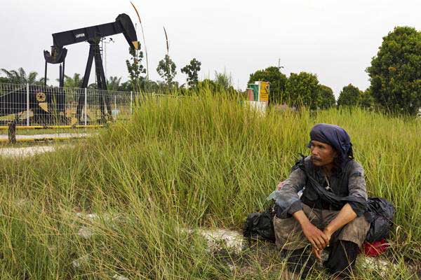 Warga beristirahat di dekat monumen pompa angguk minyak tertua di daerah Minas yang masuk dalam Blok Rokan di Riau, Rabu (1/8/2018). - ANTARA/FB Anggoro