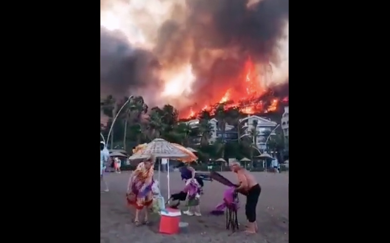 Tangkapan layar video yang menunjukkan para turis di pesisir Antalya tampak mengemasi barang setelah api yang membakar hutan pinus di wilayah tersebut kian membesar - Twitter