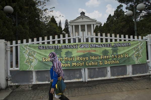 Perempuan melintas di depan spanduk ucapan selamat Idul Fitri di depan Gereja Immanuel, Jakarta, Rabu (22/7). - Antara