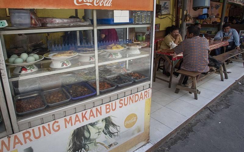 Sejumlah warga menyantap sajian yang dijual salah satu warung makan di Kemayoran, Jakarta, Senin (26/7/2021). Pemerintah menyesuaikan aturan Pemberlakuan Pembatasan Kegiatan Masyarakat (PPKM) level 4 pada pelaku usaha kuliner dengan mengizinkan warung makan, pedagang kaki lima, lapak jajanan dan sejenisnya untuk buka dengan protokol kesehatan yang ketat sampai dengan pukul 20.00, menerima maksimal pengunjung makan di tempat tiga orang dan waktu makan maksimal 20 menit. ANTARA FOTO - Aditya Pradana Putra