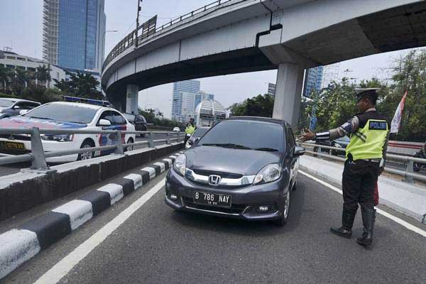Petugas Ditlantas Polda Metro Jaya memberhentikan mobil berpelat nomor genap yang memasuki Jalan Gatot Soebroto, Jakarta, Rabu (1/8/2018). - ANTARA/Hafidz Mubarak A