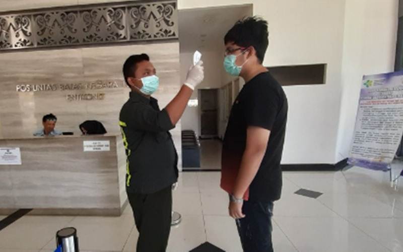 Ilustrasi-Seorang petugas Kantor Kesehatan Pelabuhan (KKP) Entikong mengukur suhu tubuh pelintas batas yang hendak ke Malaysia di Pos Lintas Batas Negara (PLBN) Entikong di Kabupaten Sanggau, Kalimantan Barat, Jumat (13/3/2020). - ANTARA/AGUS ALFIAN