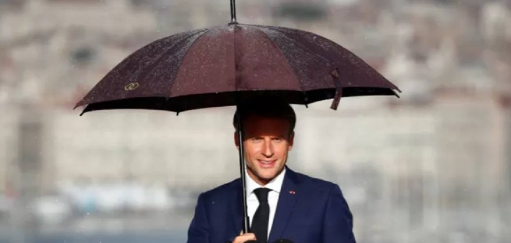 Presiden Prancis Emmanuel Macron memakai payung saat ia memberikan pidato di Palais du Pharo di Marseille, Prancis, Kamis (2/9/2021). - Antara/Reuters.