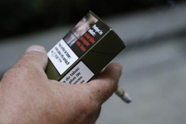 Seorang pria memegang kemasan rokok di Paris (25/9/2014) - Istimewa