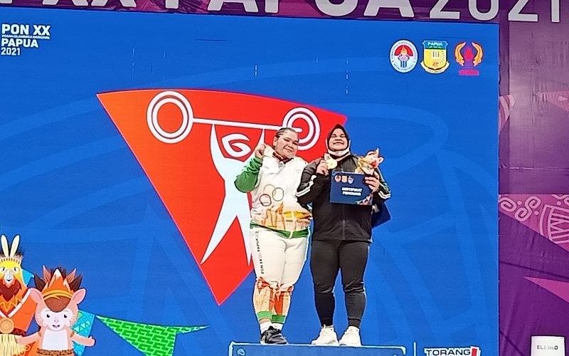 Lifter Olimpiade Nurul Akmal (kanan) berbagi podium kemenangan dengan lifter Riska Oktaviana usai tampil di kelas 87kg angkat besi putri PON XX Papua yang digelar di Universitas Cenderawasih, Jayapura, Sabtu (9/10/2021). - ANTARA/Andi Firdaus.