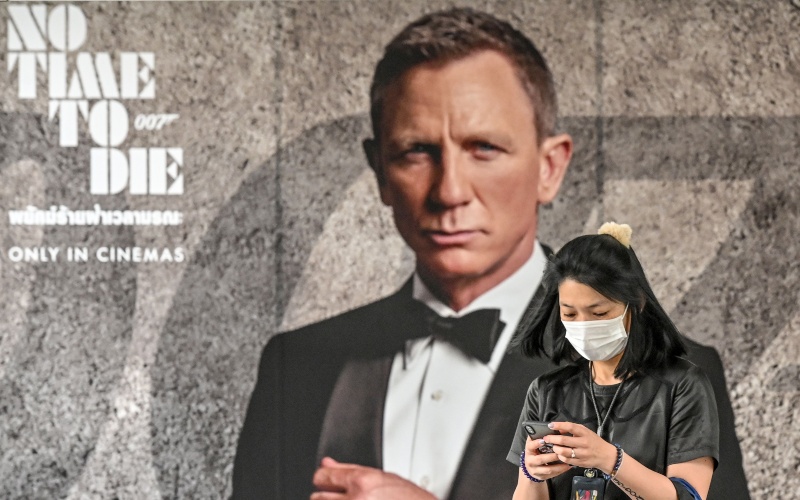 Warga melintas di depan poster film James Bond No Time to Die - Bloomberg