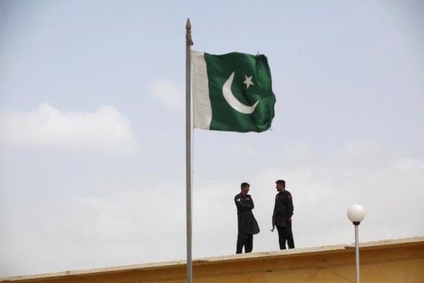 Tentara Pakistan berbincang di dekat bendera Pakistan yang berkibar di penjara Karachi, Pakistan, Jumat (23/8/2013). - Reuters/Akhtar Soomro