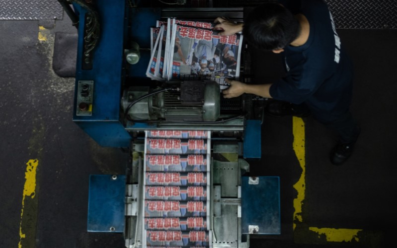 Pekerja sedang mengoperasikan mesin cetak koran. - Bloomberg