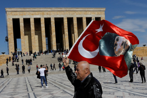 Seorang pria mengibarkan bendera Turki dengan potret Mustafa Kemal Ataturk di depan Anitkabir, tempat peristirahatan Ataturk, di Ankara, Turki, Selasa (2/4/2019). - Reuters/Umit Bektas