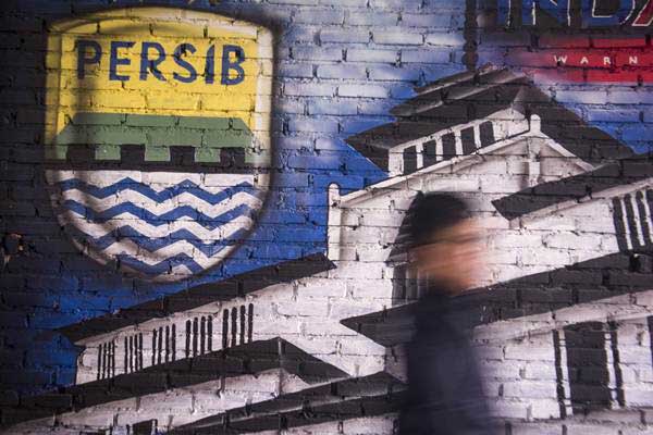 Bobotoh alias pendukung Persib berjalan di depan mural Persib di Bandung - Antara