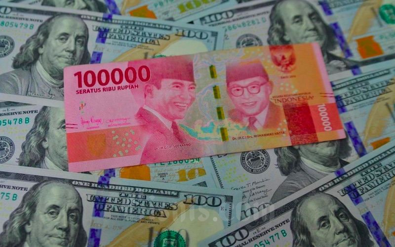 Petugas menunjukkan mata uang dolar AS dan rupiah di Money Changer, Jakarta, Senin (19/4/2021). Bisnis - Fanny Kusumawardhani
