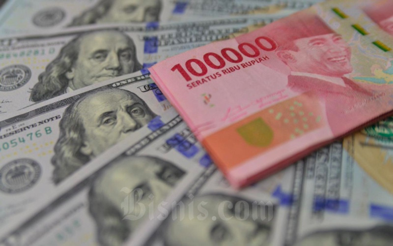 Petugas menunjukkan mata uang dolar AS dan rupiah di Money Changer, Jakarta, Senin (19/4/2021). Bisnis - Fanny Kusumawardhani