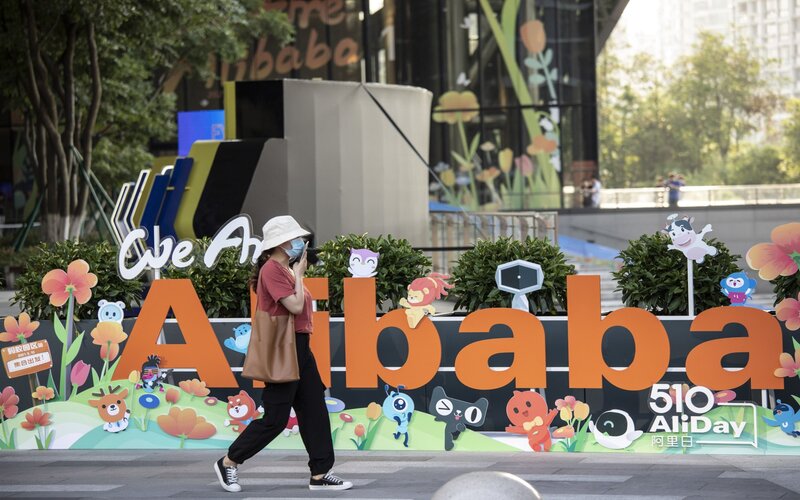 Seorang pejalan kaki melewati logo Alibaba di China.  - Bloomberg