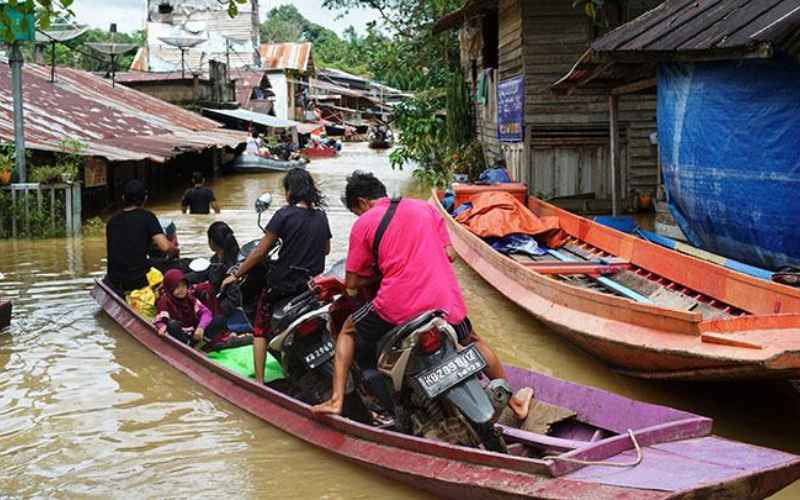 Sejumlah warga menaiki perahu melintasi banjir yang merendam permukiman di Desa Lesabela, Kecamatan Ledo, Kabupaten Bengkayang, Kalimantan Barat, Jumat, 5 Februari 2021. Banjir ini mengakibatkan akses menuju perbatasan terputus/ ANTARA/HO - Andas