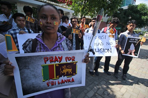Mahasiswa Universitas Muhammadiyah Surabaya membawa poster dan bunga saat melakukan aksi solidaritas untuk korban bom Sri Lanka di Surabaya, Jawa Timur, Senin (22/4/2019). Aksi tersebut merupakan bentuk kepedulian terhadap korban terorisme dan menolak segala bentuk kejahatan yang mengatasnamakan agama. ANTARA FOTO - Moch Asim
