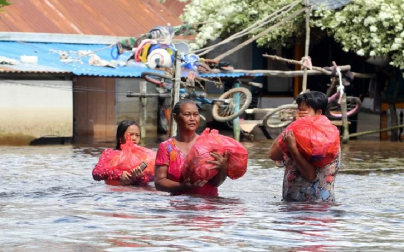 Sejumlah warga korban banjir membawa bungkusan sembako saat melintasi permukiman di tepian Sungai Kapuas, Sintang, Kalimantan Barat, Kamis (18/11/2021). - Antara