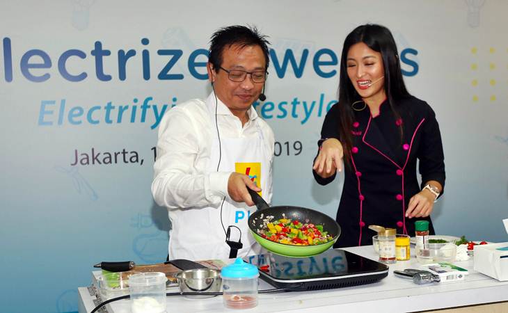 Kepala Divisi Niaga PLN Yudi Setyo Wicaksono (kiri) disaksikan Chef Priscil mencoba kompor induksi saat acara Elektrizen weeks di Jakarta, Senin (18/3/2019). - Bisnis/Abdullah Azzam