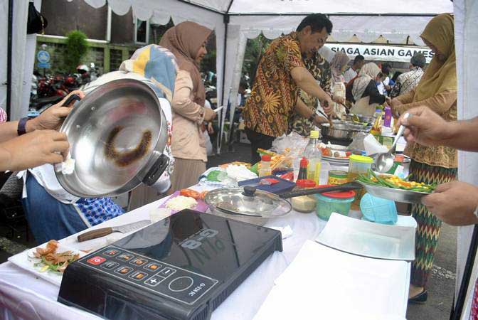 Sejumlah peserta memasak menggunakan kompor induksi di halaman kantor PLN UP3 Kota Bogor, Jawa Barat, Jum'at (15/2/2019). - ANTARA/Arif Firmansyah