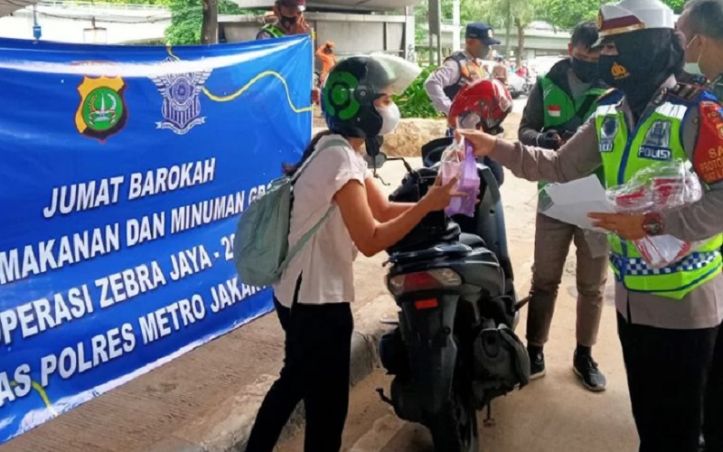 Pengendara yang ditegur dalam Operasi Zebra Jaya 2021 di Tomang diberi sarapan oleh polisi, Jumat pagi (19/11/2021). - Antara