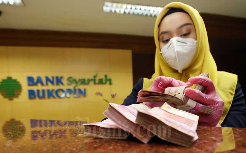Karyawan menghitung mata uang rupiah di Bank Bukopin Syariah, Jakarta, Kamis (11/2/2021). Bisnis - Abdullah Azzam