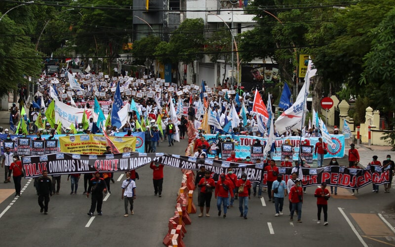 Buruh membentangkan spanduk dan poster saat berunjuk rasa di Jalan Basuki Rahmat, Surabaya, Jawa Timur, Senin (29/11/2021). Mereka menuntut perbaikan Upah Minimum Provinsi (UMP). - Antara/Didik Suhartono