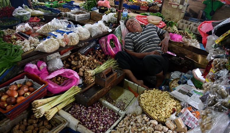 Pedagang aneka bahan bumbu masakan tertidur saat menunggu calon pembeli di Pasar Minggu, Jakarta Selatan, Senin (27/1/2020). -  ANTARA / Sigid Kurniawan