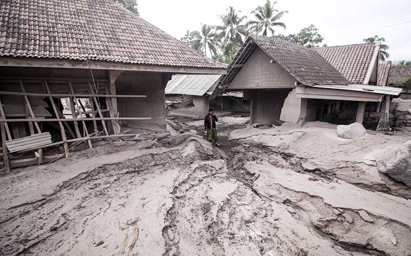 Warga melintas di rumah yang rusak akibat abu vulkanik letusan Gunung Semeru di Desa Sumber Wuluh, Lumajang, Jawa Timur, Minggu (5/12/2021). Akibat letusan Gunung Semeru tersebut sedikitnya puluhan rumah rusak. ANTARA FOTO - Umarul Faruq