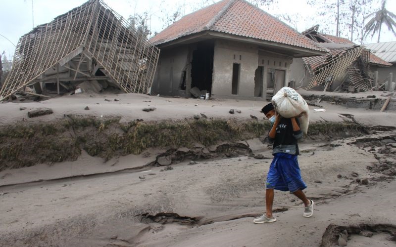 Seorang warga mengangkut barang yang bisa diselamatkan dari rumahnya yang hancur akibat erupsi gunung Semeru yang meluncurkan awan panas di desa Supiturang, Lumajang, Jawa Timur, Minggu (5/12/2021). Luncuran awan panas akibat letusan gunung Semeru mengakibatkan puluhan rumah di dua kecamatan rusak dan delapan kecamatan terdampak abu vulkanik. ANTARA FOTO/Ari Bowo Sucipto - foc