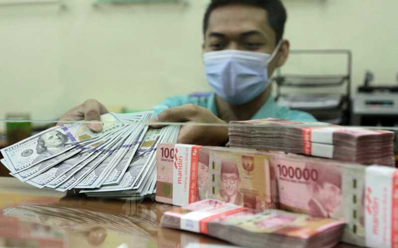 Pegawai menunjukan uang dolar dan rupiah di Jakarta, Senin (15/2/2021). Bisnis - Himawan L Nugraha