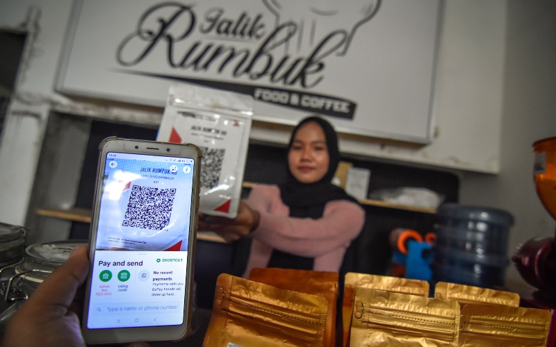 Seorang warga menggunakan pembayaran nontunai Quick Response Indonesia Standard (QRIS) saat membeli kopi di warung kopi Jalik Rumbuk di Mataram, NTB, Selasa (12/1/2021). - Antara/Ahmad Subaidi