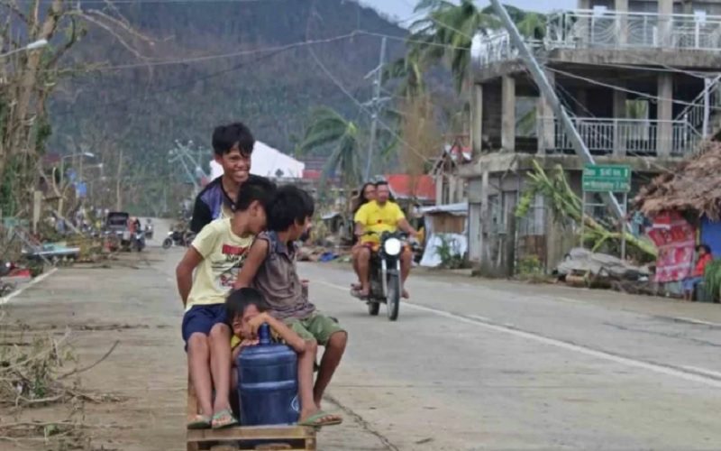 Anak-anak naik kereta darurat di dekat jalan yang rusak di Provinsi Surigao del Norte, Filipina, Sabtu (18/12/2021). Setidaknya 75 orang dilaporkan tewas setelah topan Rai melanda sebagian besar wilayah Filipina dan ratusan ribu warga diperkirakan mengungsi ke tempat yang lebih aman. - Antara/Reuters