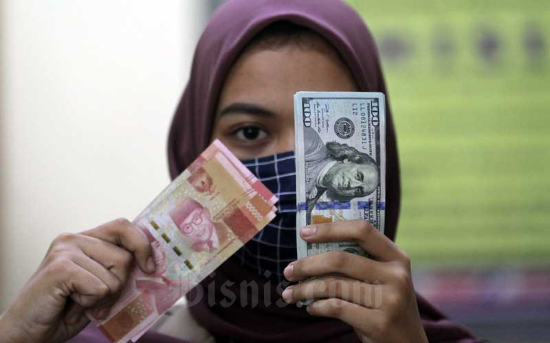 Karyawati menunjukan uang Rupiah dan dolar AS di salah satu gerai penukaran mata uang asing di Jakarta, Minggu (7/6/2020). Bisnis - Arief Hermawan P