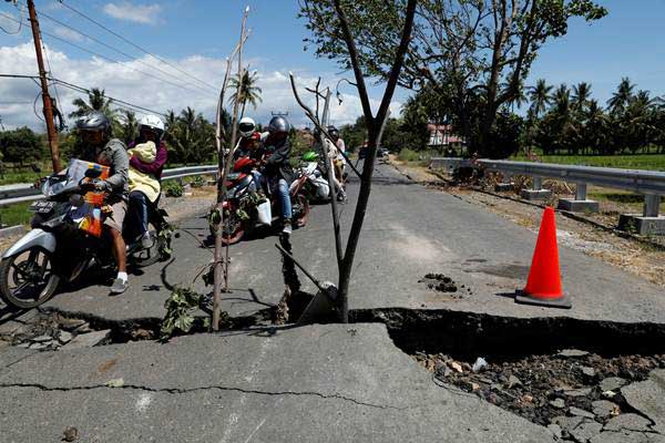 Warga mengendarai sepeda motor menghindari jalan yang rusak akibat gempa, di Lombok Utara, NTB, Selasa (7/8/2018). - Reuters/Beawiharta