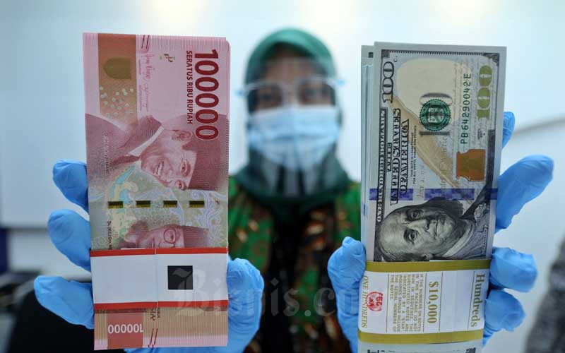 Karyawan menunjukan Rupiah dan Dolar AS di Jakarta, Rabu (27/1/2021). Nilai tukar rupiah di pasar spot ditutup menguat 15 poin atau 0,11 persen menjadi Rp14.050 per dolar AS. Bisnis - Eusebio Chrysnamurti