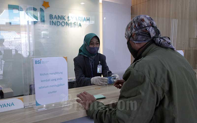 Karyawan melanyani nasabahyang melakukan transaksi di PT Bank Syariah Indonesia KC Jakarta Barat, Kebon Jeruk, Jakarta, Senin (1/2 - 2021). Bisnis