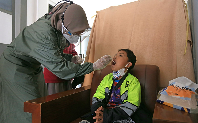 Petugas melakukan tes PCR kepada penumpang anak-anak sebelum melakukan perjalanan kereta api di Stasiun Jatibarang, Indramayu, Jawa Barat, Sabtu (25/12/2021).  - Antara Foto/Dedhez Anggara/YU