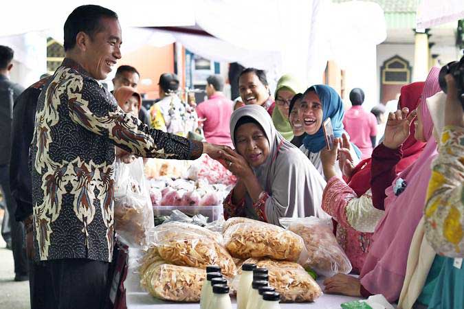 Pemerintah akan memberikan bantuan sosial atau bansos tahun ini, 2022. Presiden Joko Widodo (kiri) berjabat tangan dengan penerima Bantuan Sosial Program Keluarga Harapan (PKH) 2019 di Sukmajaya, Depok. - ANTARA FOTO/Puspa Perwitasari