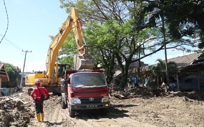 Tim dari PT Brantas Abipraya melakukan proses pembersihan Jalan Salawati Daud, Kecamatan Masamba, Kabupaten Luwu Utara, Sulawesi Selatan yang masih tertutup material kayu dan lumpur (19/7/2020). - Dok. BNPB